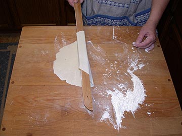 Turning the lefse again with the one-edged lefse stick