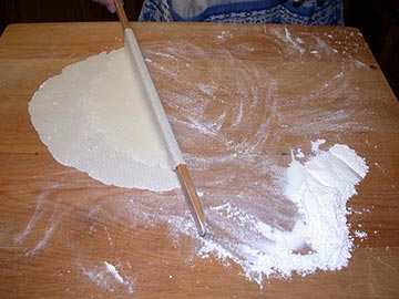 Turning the lefse again with the one-edged lefse stick